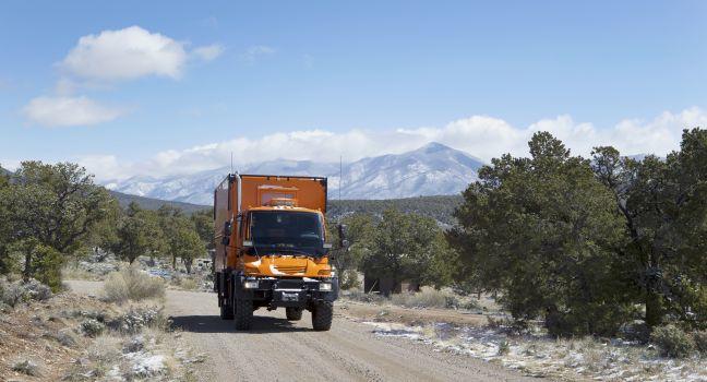 WILD RIVERS RECREATIONAL AREA, NEW MEXICO, USA - April 15: Custom orange RV truck driving on snowy dirt road on April 15, 2014 at Wild Rivers Recreational Area, New Mexico, USA.  