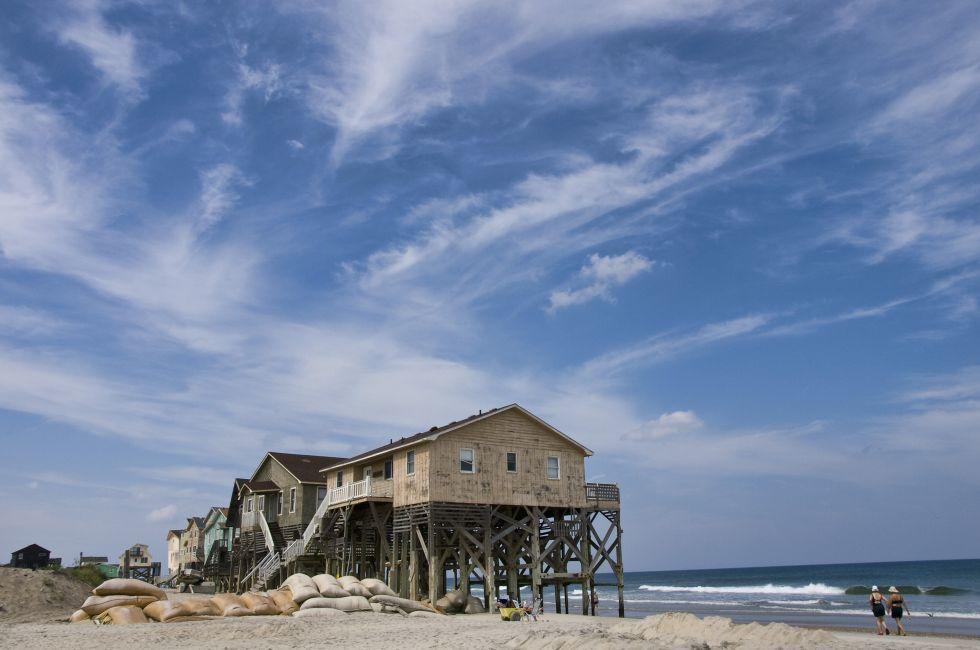 View from the beach showing a beautiful cloudscape and the sand bags around a row of condemned homes in Nags Head North Carolina in the Outer Banks.