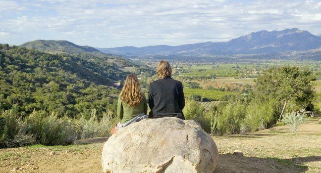 Couple sits and meditates at Meditation Mount's Point overlooking the Ojai Valley, CA