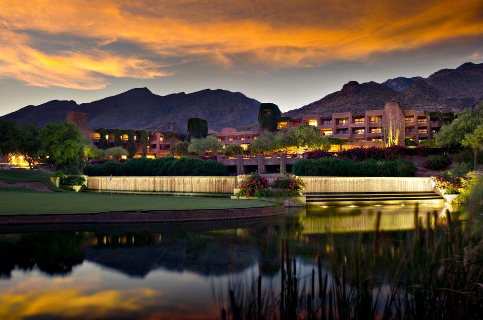 Long exposure of a luxury hotel resort. A golf course and pond is in the foreground and foothill mountains in the background.