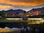 Long exposure of a luxury hotel resort. A golf course and pond is in the foreground and foothill mountains in the background.