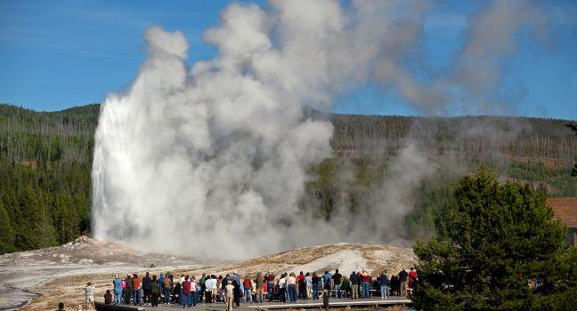 Tourists watching the Old Faithful erupting in Yellowstone National Park.
