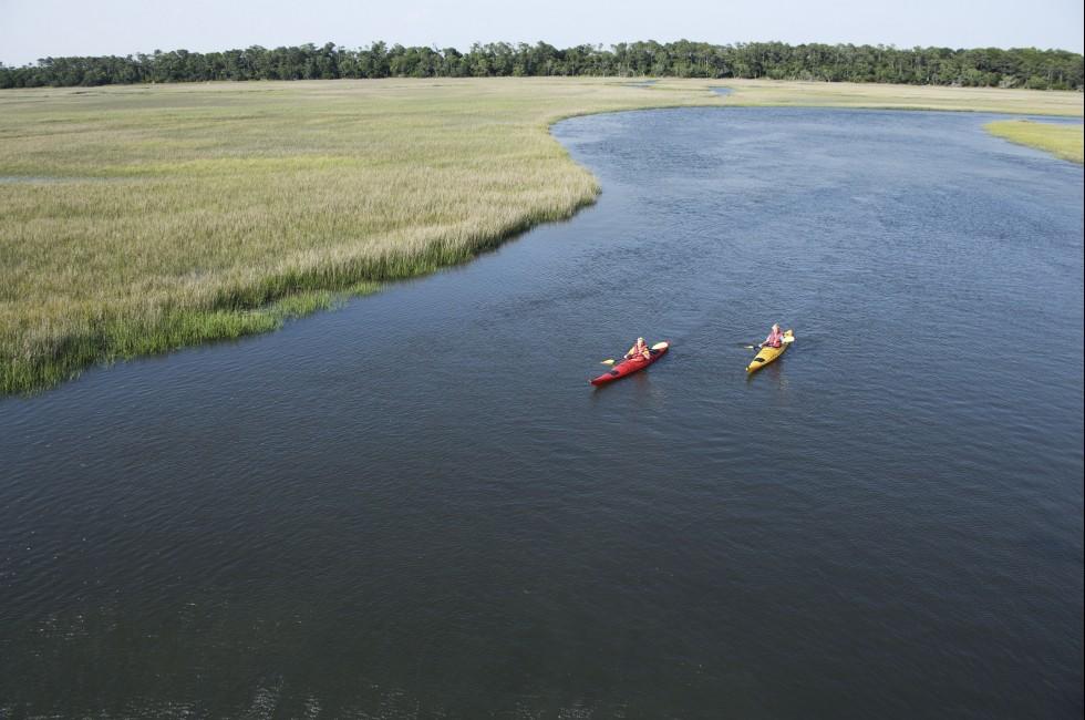 Aerial of two teenage boys kayaking through marshland on Bald Head Island, North Carolina.