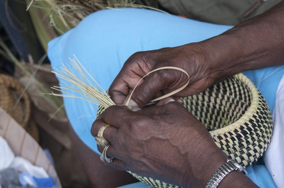 Hands weaving sweetgrass into beautiful baskets.