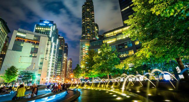 Fountains and buildings at night at Columbus Circle, in Manhattan, New York.