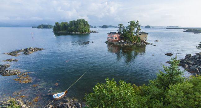 Beautiful calm summer, seascape with boat and houses on tiny forested islands in Sitka Sound on Baranof Island, Alaska.