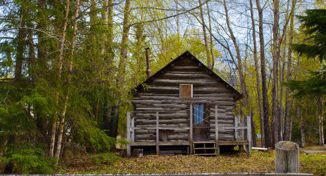 Old cabin in front of mountain in Hope Alaska an old mining town with a front porch.
