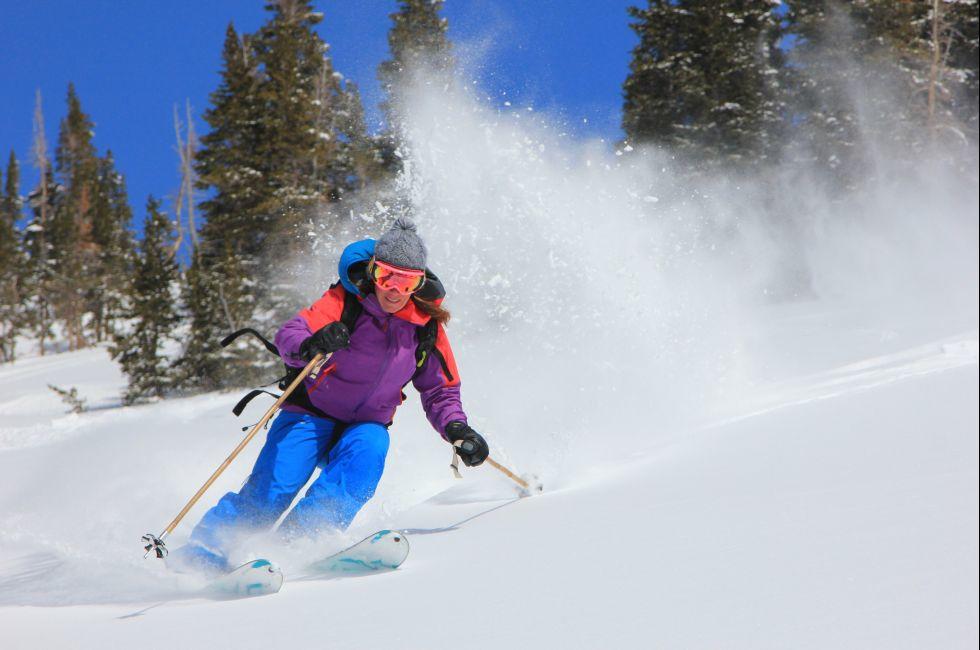 Expert female skier blasting through deep powder snow in the Utah mountains, USA.