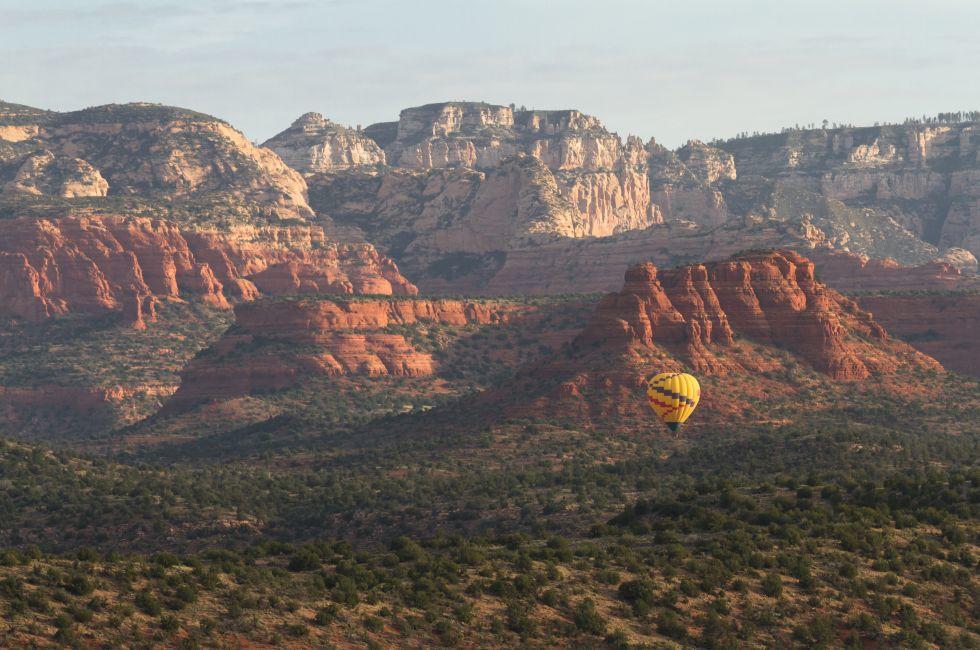 Aerial view of Sedona Arizona with a Hot air balloon soaring thru the red rock landscape.