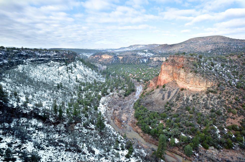 A beautiful high desert canyon with a flowing river, pine trees and snow in Greer Arizona.