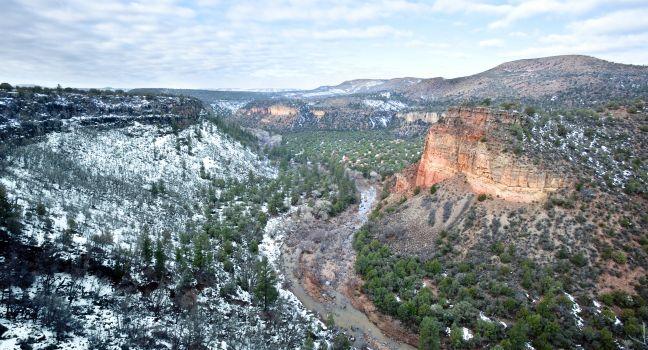 A beautiful high desert canyon with a flowing river, pine trees and snow in Greer Arizona.
