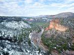 A beautiful high desert canyon with a flowing river, pine trees and snow in Greer Arizona.