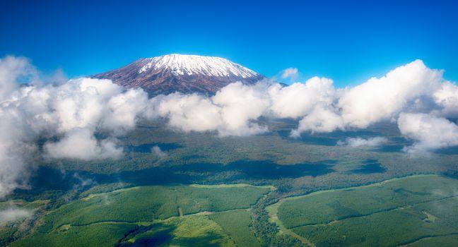 Aerial image of Mount Kilimanjaro, Africa's highest mountain, with snow and white puffy clouds from Kenya
