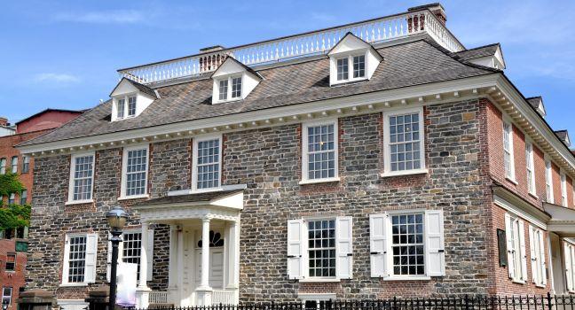 The field stone south front and wooden portico doorway of Georgian era Philipsburg Manor built in 1693 in Yonkers, New York.