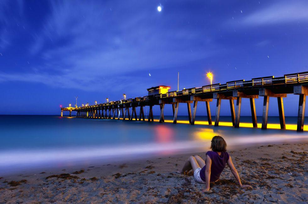 woman sitting on Venice Beach, Florida at night, time exposure; 
