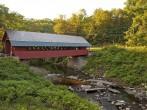 Creamery covered bridge built in 1879 in Brattleboro Vermont. Beautiful historic red covered bridge with a flowing stream of water below it.