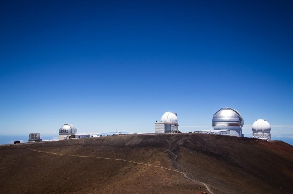 Observatory dome at the peak of Mauna Kea volcano, Hawaii. Telescope structure on volcano top above the main cloud layert.