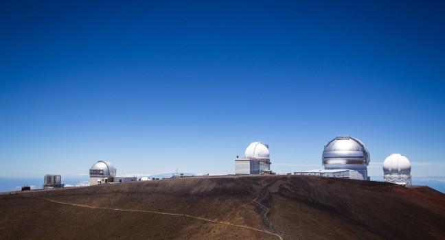 Observatory dome at the peak of Mauna Kea volcano, Hawaii. Telescope structure on volcano top above the main cloud layert.