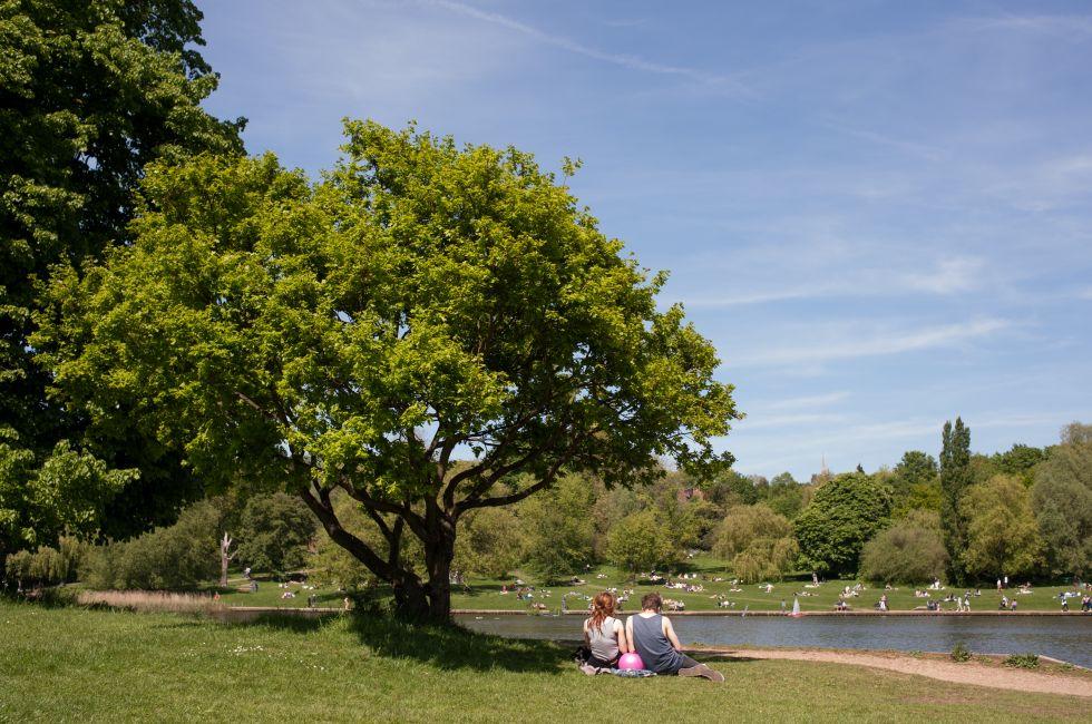 A young couple relaxing on the grass in Hampstead Heath during the summer months in London.