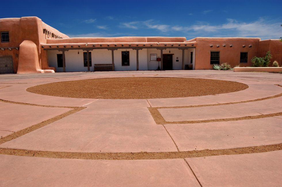A traditional adobe building located on Museum Hill in Santa Fe, New Mexico. Front plaza area shows unusual paving detail.