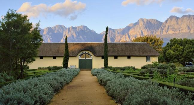African boer house against misty mountains in sunset light. Shot in Vergelegen wine farm/estate, near Stellenbosch, Western Cape, South Africa