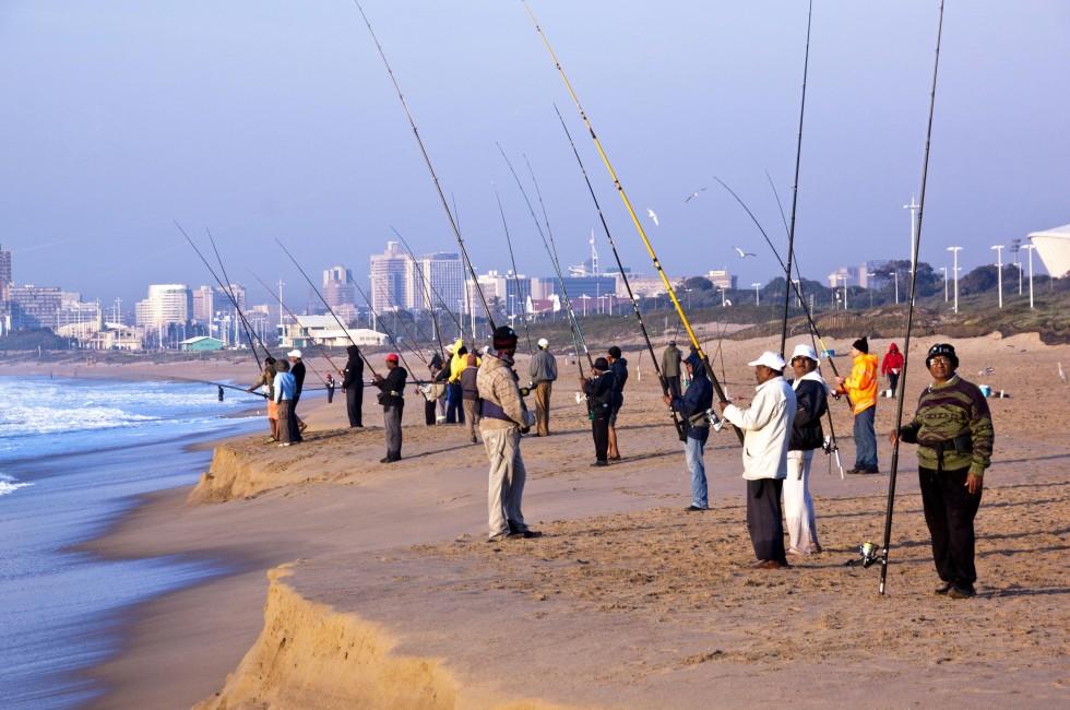 DURBAN, SOUTH AFRICA - JULY 2, 2014: Many unknown early morning fishermen fish on Blue Lagoon beach in Durban South Africa; 