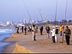 DURBAN, SOUTH AFRICA - JULY 2, 2014: Many unknown early morning fishermen fish on Blue Lagoon beach in Durban South Africa; 