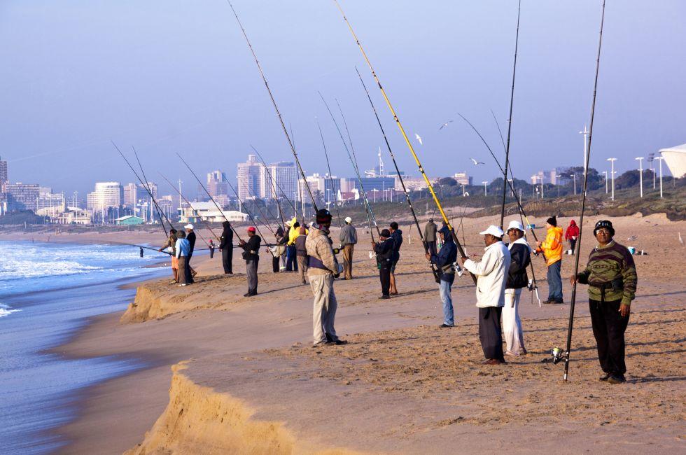 DURBAN, SOUTH AFRICA - JULY 2, 2014: Many unknown early morning fishermen fish on Blue Lagoon beach in Durban South Africa; 