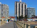 DURBAN; SOUTH AFRICA - MAY 3; 2014: People walk along concrete pier towards commercial and residential buildings on beachfront in Durban South Africa;