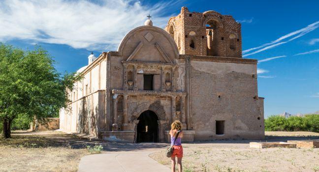 A woman visitor take a picture of the preserved Spanish mission at Tumacacori, Arizona.
