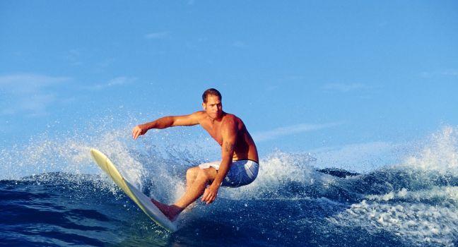 Photo of surfer Chris Gagnon riding a longboard while surfing at Waikiki Beach in Hawaii.