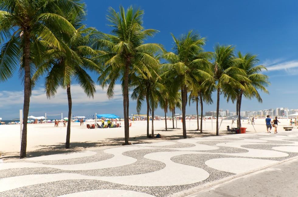 View of Copacabana beach with palms and mosaic of sidewalk in Rio de Janeiro. Brazil